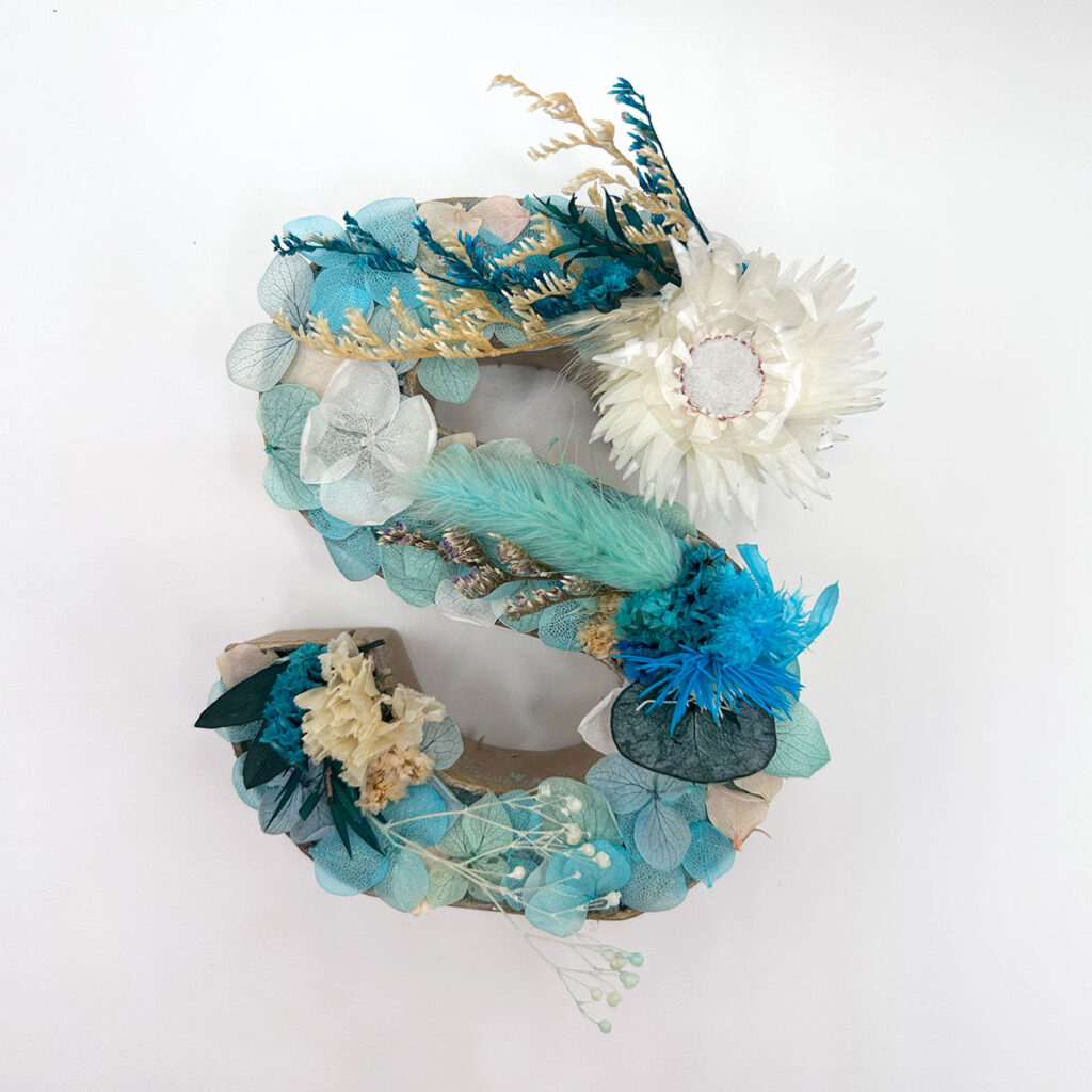 Letra de flores preservadas en tonos azules